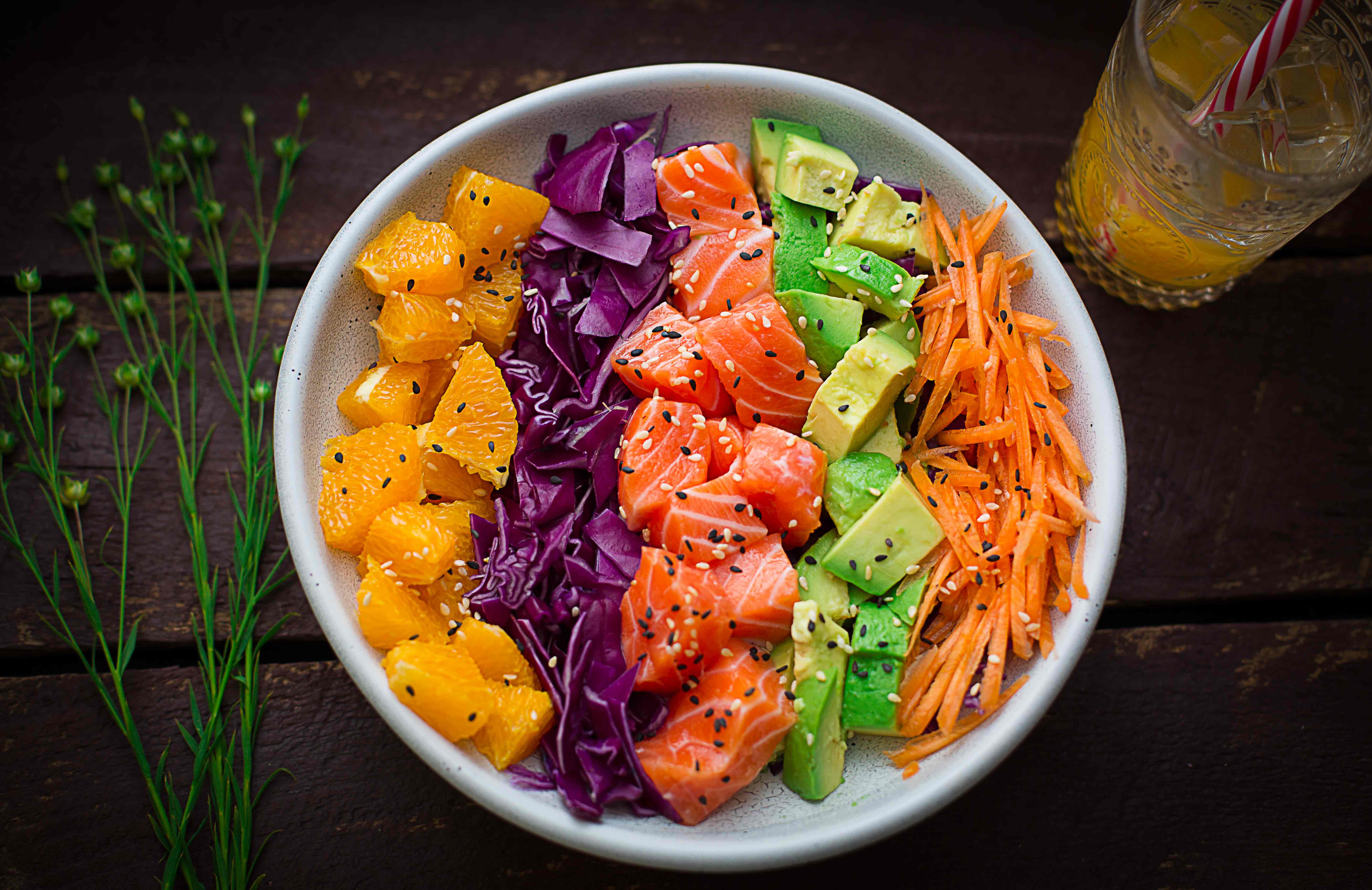 Salmon poke bowl: raw salmon pairing fresh salmon cubes with creamy avocado, sweet carrots, crunchy cabbage, and fruity oranges, all drizzled with a delicious Asian dressing. 