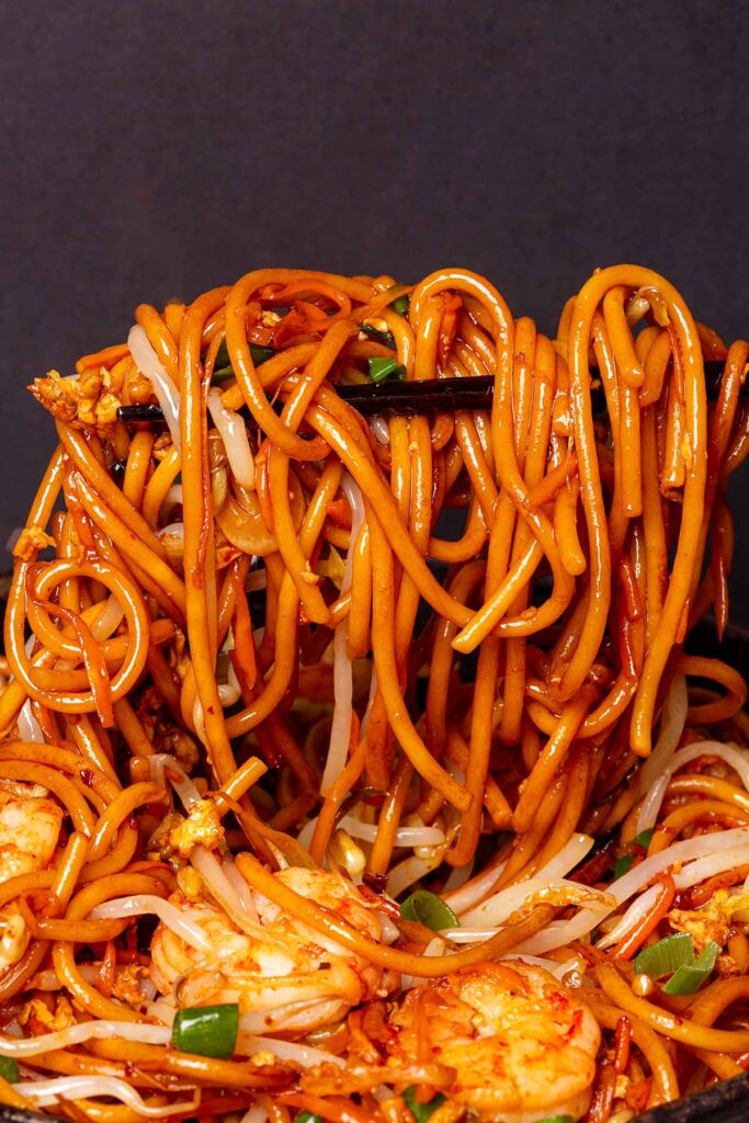A close-up of a delicious shrimp chow mein dish featuring pan-fried noodles, fusion-style fried spaghetti pasta, and plain fried noodles, highlighting the vibrant mix of spaghetti stir fry and crispy textures.